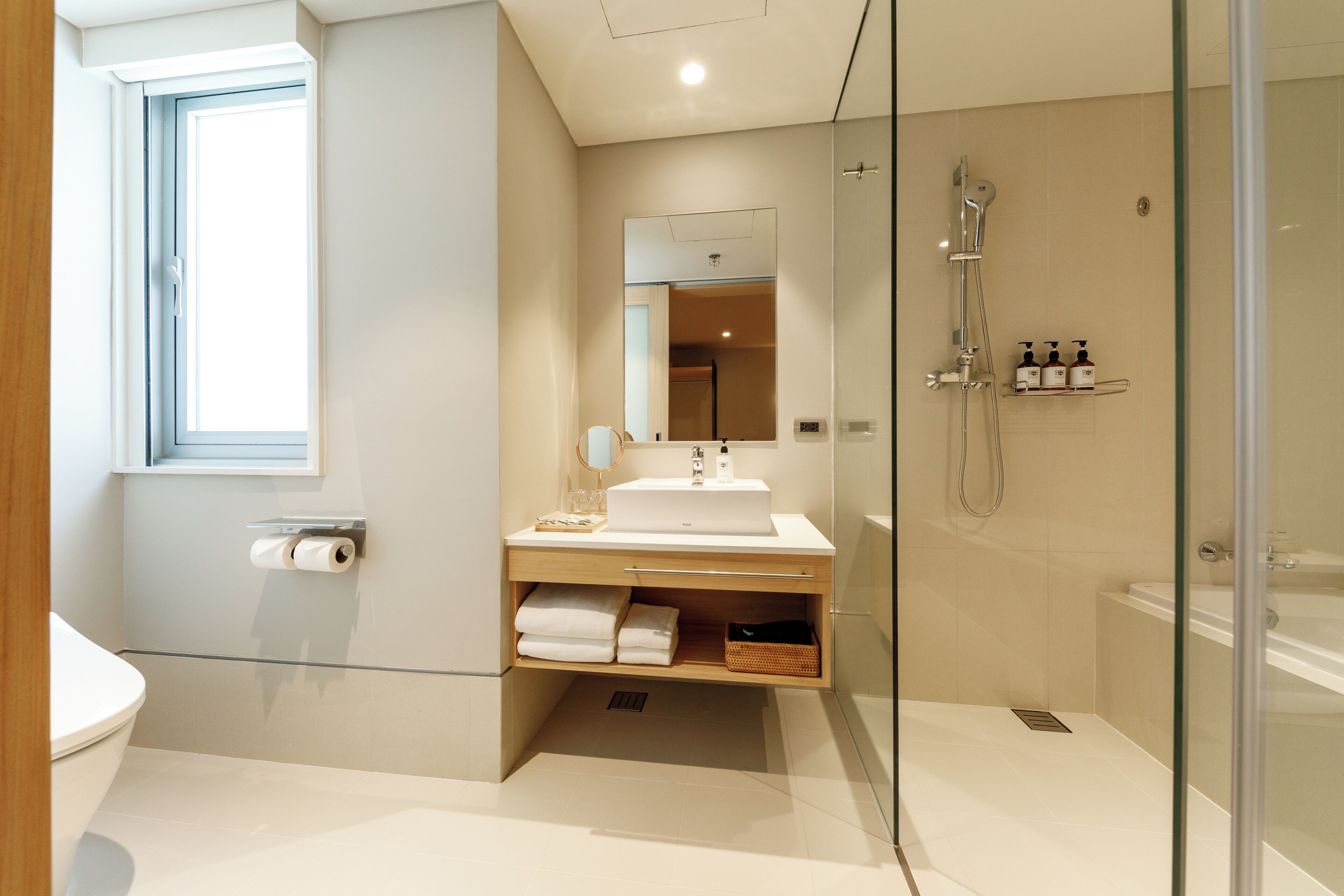 A modern bathroom with a glass-enclosed shower, a white sink, and a toilet.