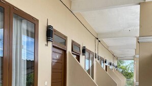 A corridor with multiple doors and windows, a trash bin, and a tiled floor.