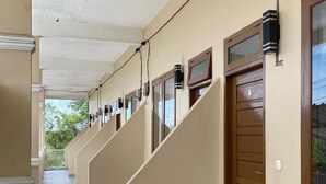 A corridor with multiple doors, each with a window and a small air conditioning unit.