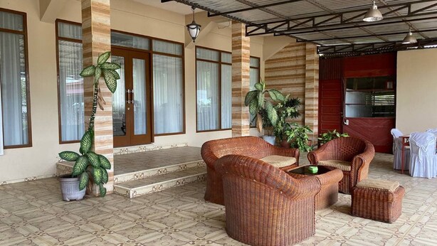 A spacious outdoor area with wicker furniture, potted plants, and a tiled floor.
