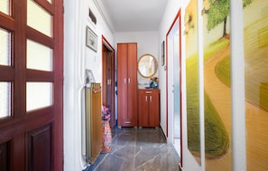A hallway with wooden doors, a welcome sign, a mirror, and a wall with abstract art.