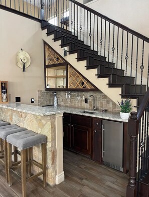 A kitchen with a stone island, dark wooden cabinets, a stainless steel dishwasher, and a black staircase with decorative railings. - 20 min from Downtown Austin ,20 min to Circuit of the Americans 10 min to Tesla (Austin)