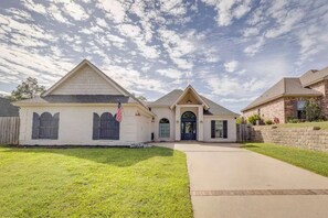 Une maison à deux étages avec un porche à l’avant, un garage et une pelouse bien entretenue.
