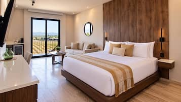 A modern bedroom with a large bed, a wooden headboard, a bedside table, a round mirror, and a view of the outdoors through a sliding door.