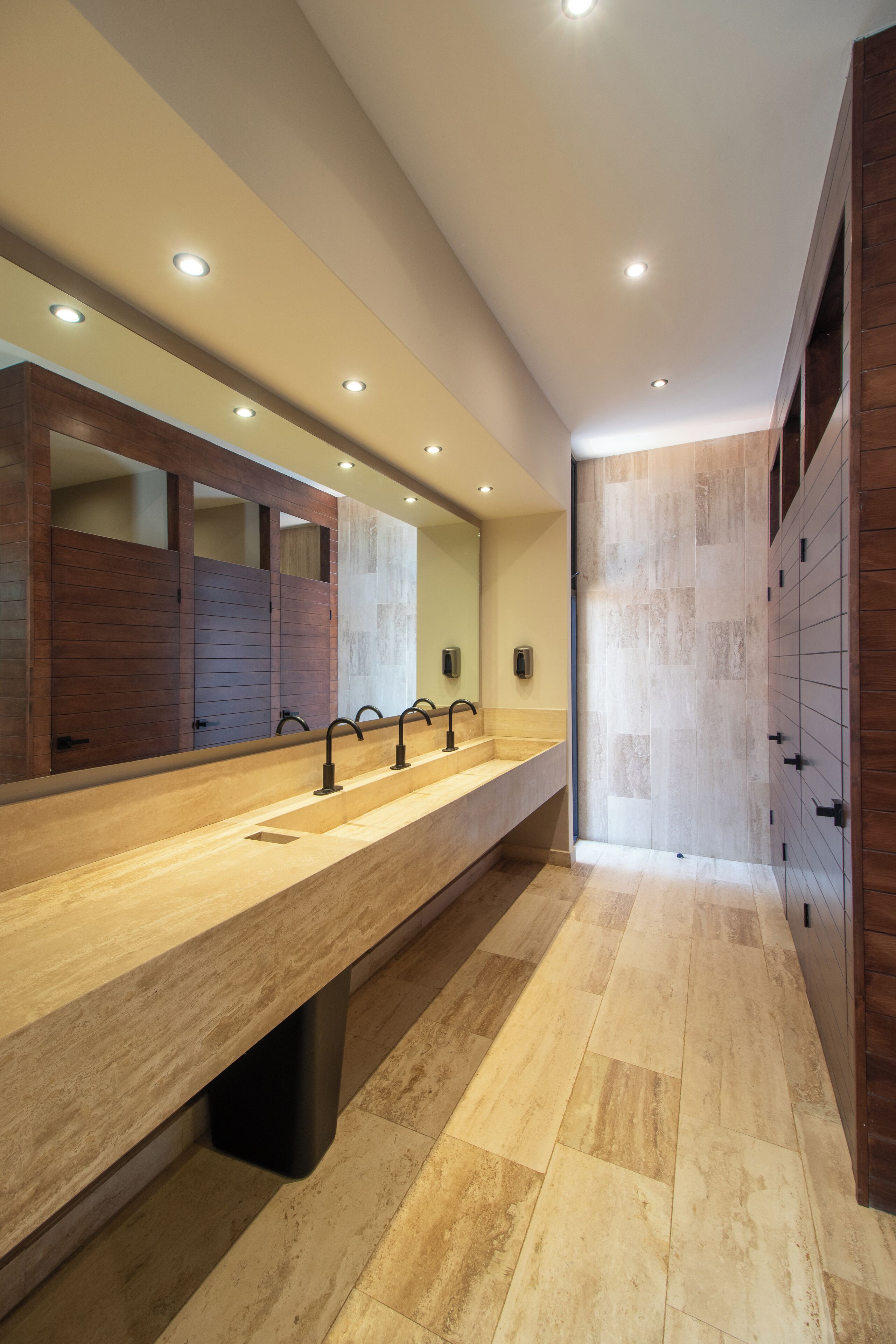A modern bathroom with a long vanity, multiple sinks, and a large mirror.