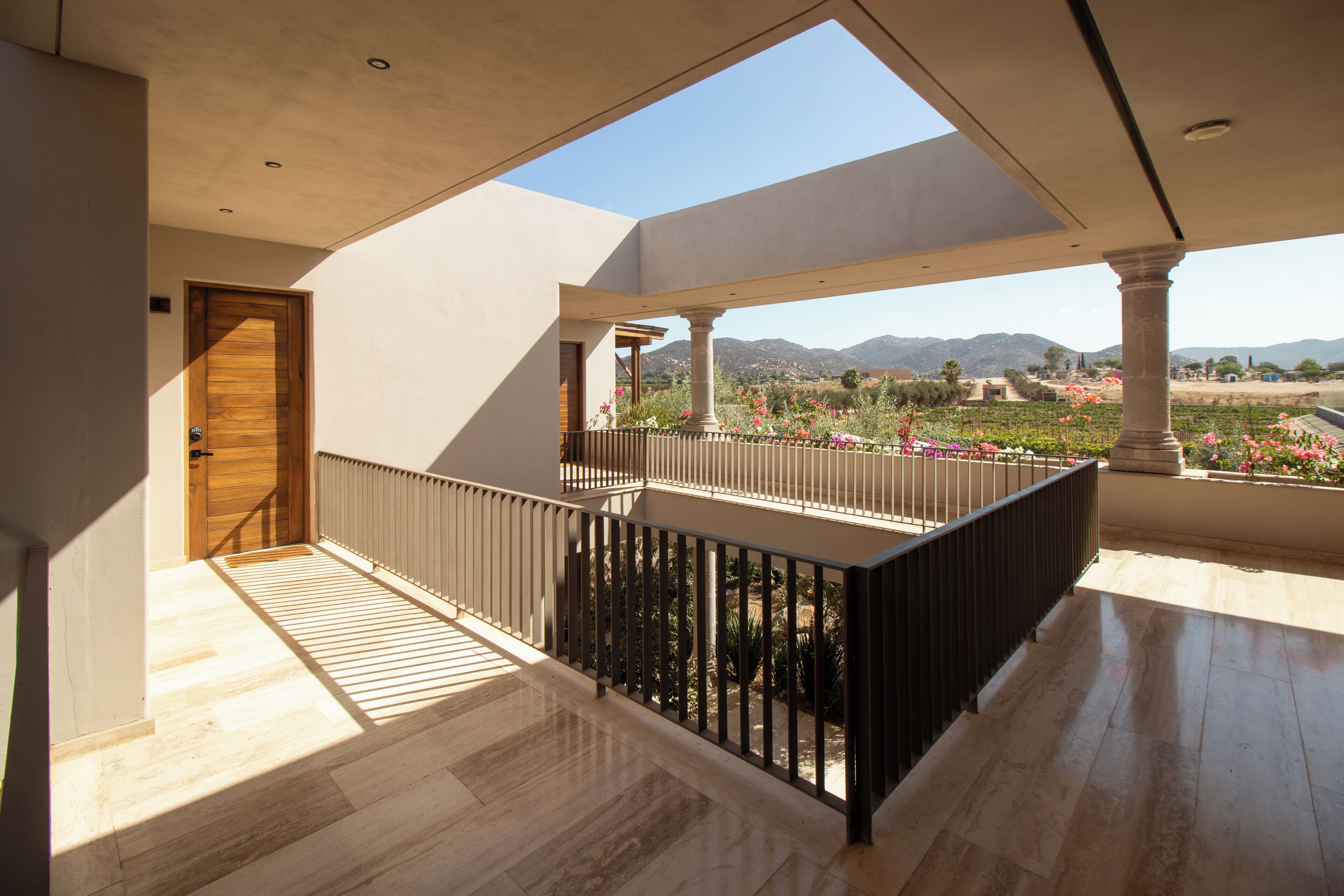 A spacious balcony with a view of a landscaped garden and distant mountains.