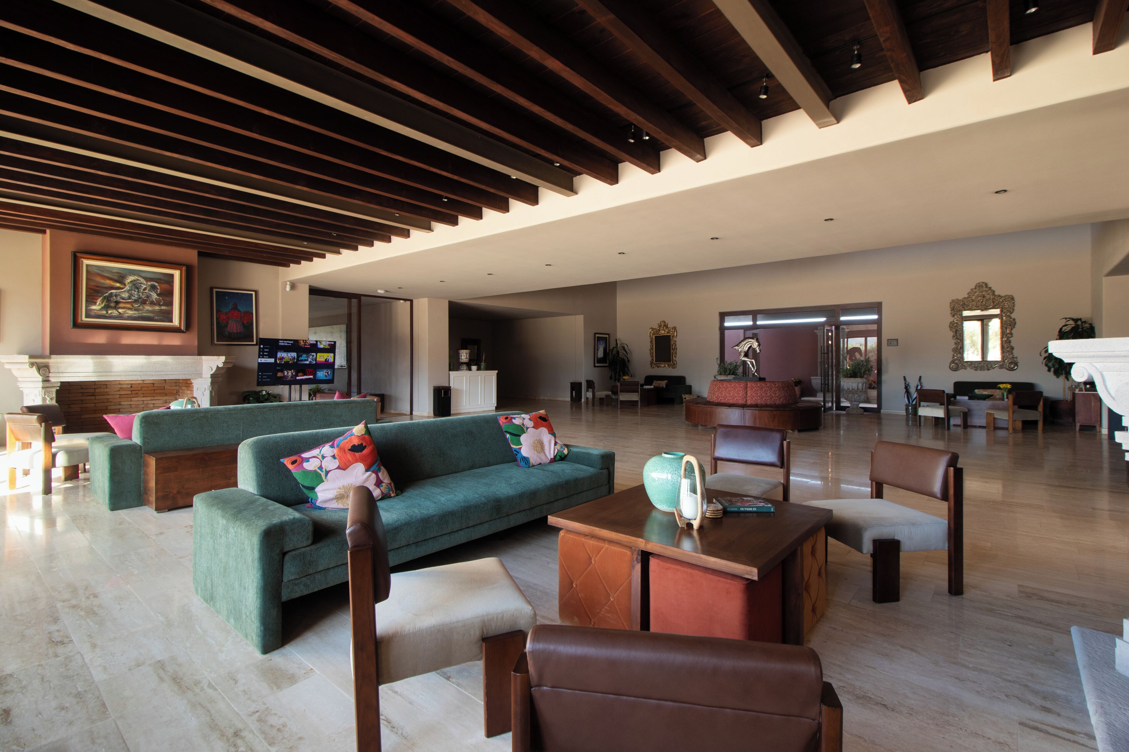 A spacious living area with a green sofa, wooden coffee table, and leather chairs.