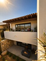 A modern outdoor patio with a fire pit, a stone wall, and a view of the mountains.