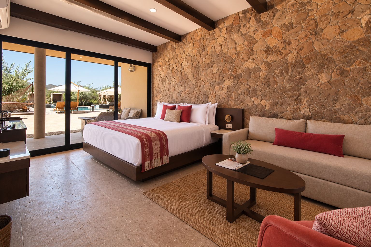 A hotel room with a bed, a sofa, a coffee table, and a stone wall.