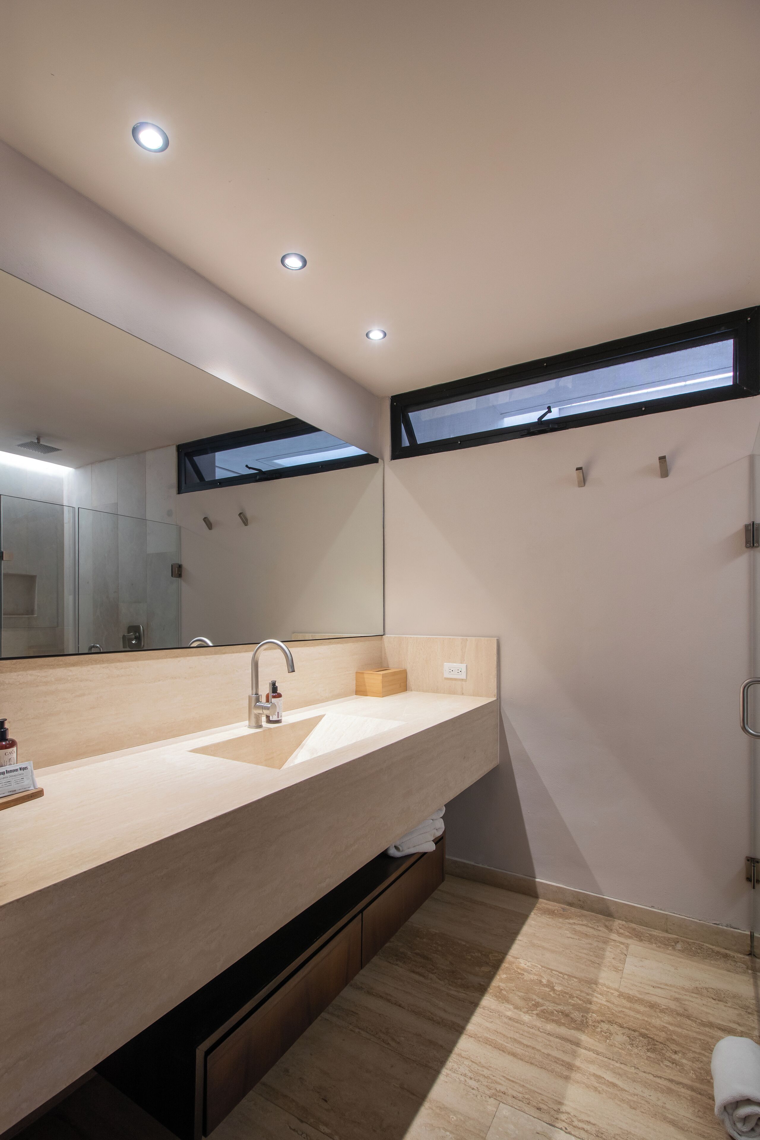 A modern bathroom with a large mirror, a sink, and a shower.