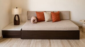 A modern bedroom with a bed, a bedside table with a lamp, and a small round table. - Hotel Flores de Sal (Valle de Guadalupe)