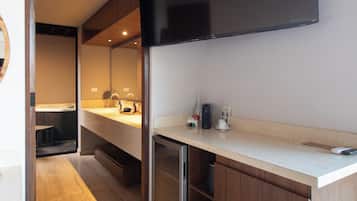A modern kitchen with a built-in oven, a microwave, and a large flat-screen TV mounted above the counter.