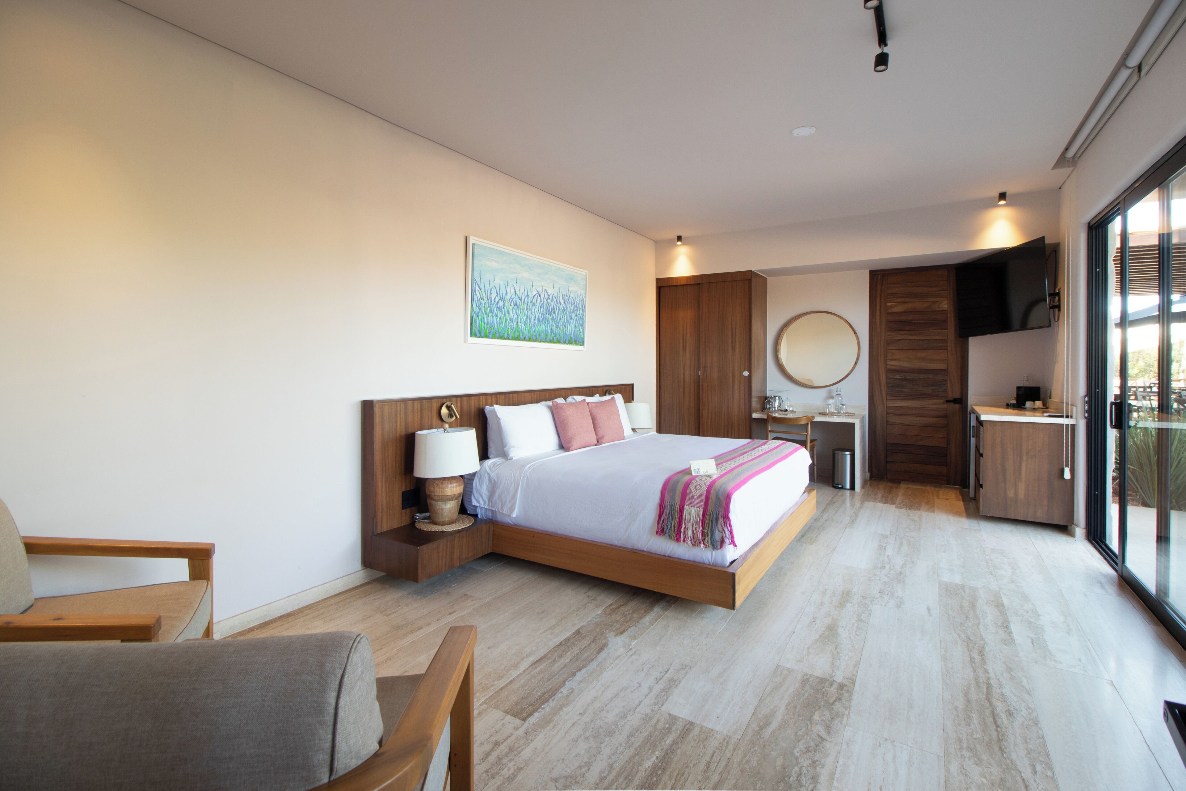 Habitación de hotel moderna con una cama grande, un escritorio, una silla y vistas a través de un ventanal.