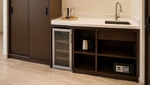 A compact kitchenette with a built-in fridge, a sink, and a coffee machine. - Hotel Flores de Sal (Valle de Guadalupe)