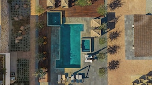 An aerial view of a modern outdoor pool area with a rectangular pool, lounge chairs, and a wooden deck. - Hotel Flores de Sal (Valle de Guadalupe)