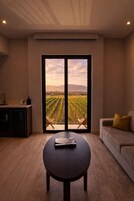 Una sala de estar moderna con un gran ventanal corredero que da a vistas de un viñedo.