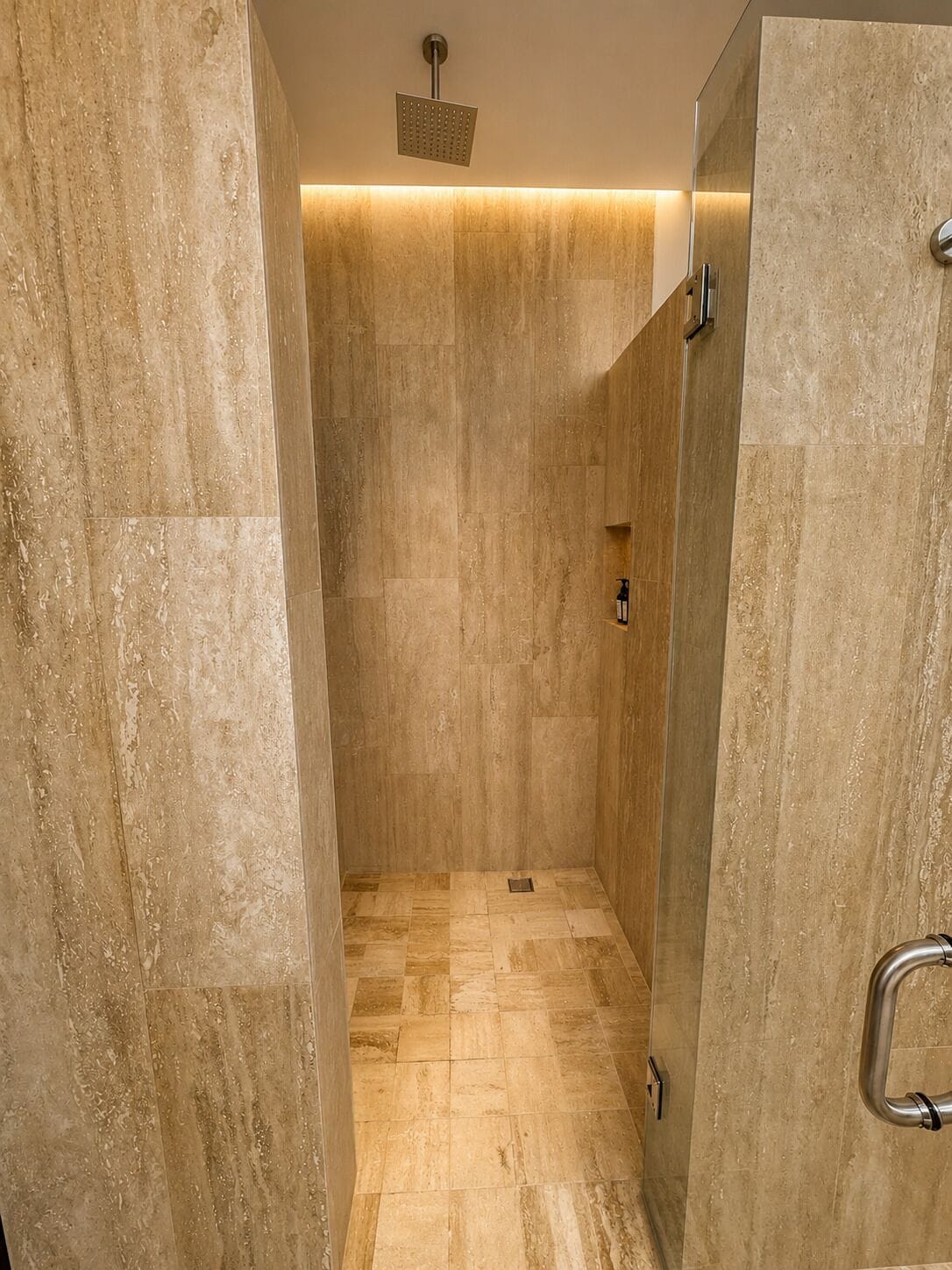 A modern shower with a square showerhead, tiled walls, and a floor with a mix of tile patterns.