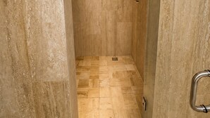A modern shower with a square showerhead, tiled walls, and a floor with a mix of tile patterns. - Hotel Flores de Sal (Valle de Guadalupe)