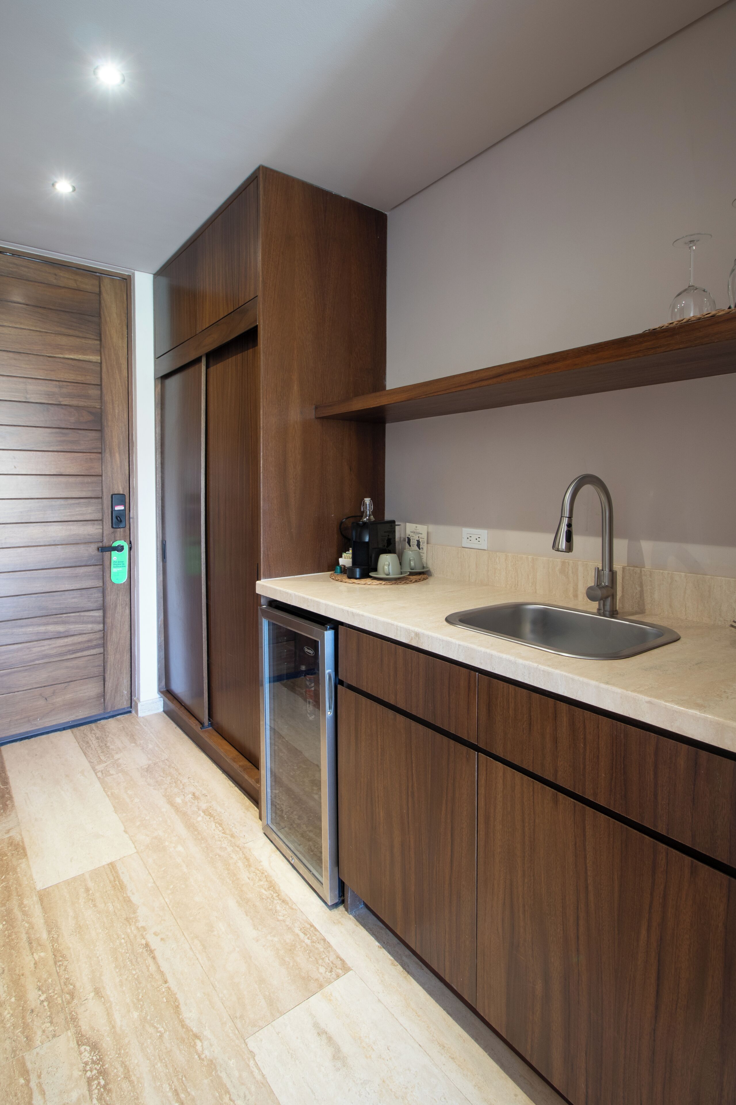 A modern kitchen with a built-in dishwasher, a stainless steel sink, and wooden cabinetry.