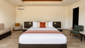 A modern hotel room with a large bed, two nightstands, a sofa, and a chair. - Hotel Flores de Sal (Valle de Guadalupe)