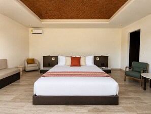 A modern hotel room with a large bed, two nightstands, a sofa, and a chair. - Hotel Flores de Sal (Valle de Guadalupe)