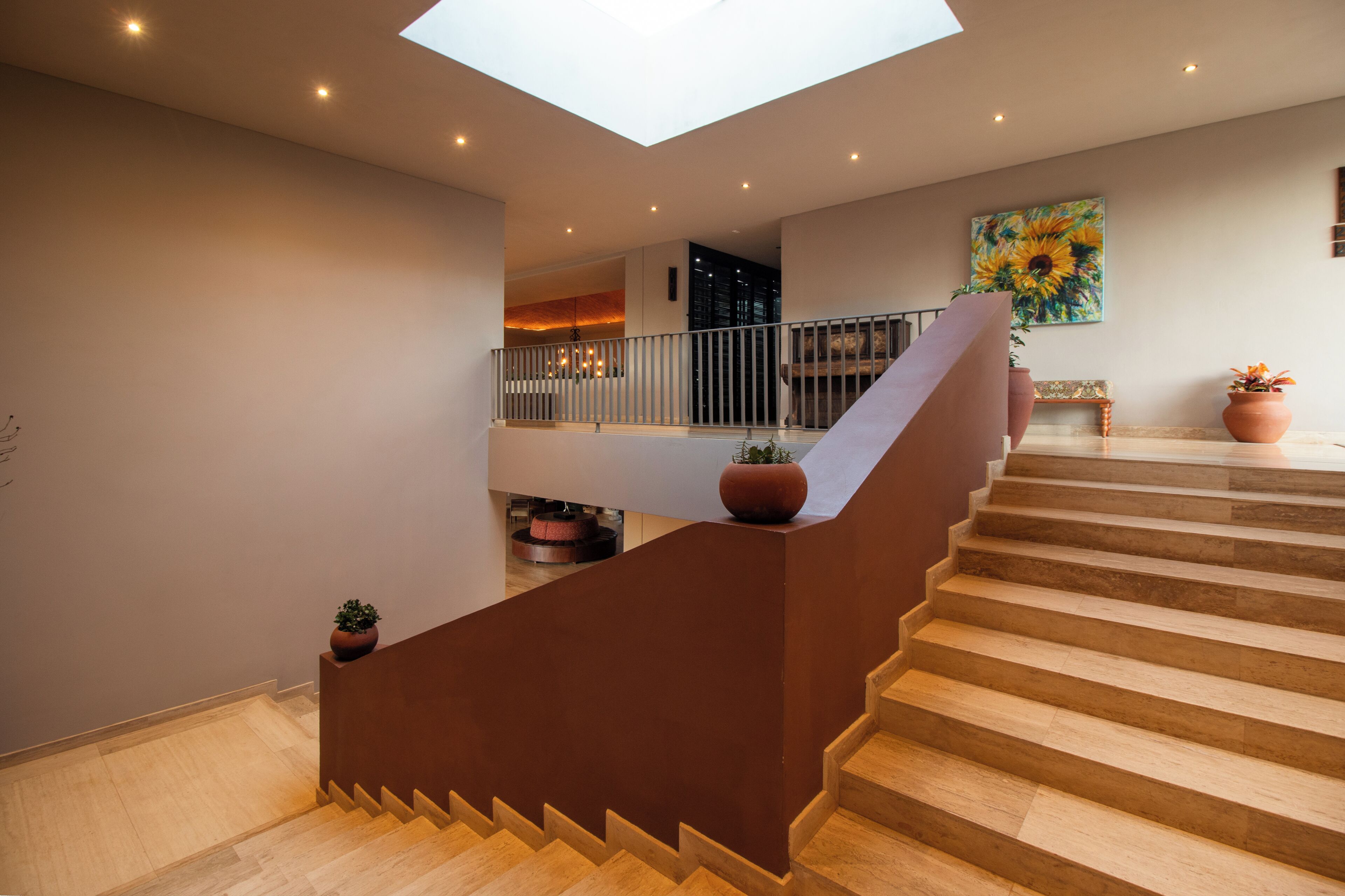 A modern staircase with a glass ceiling, leading to a second-floor balcony with a railing.