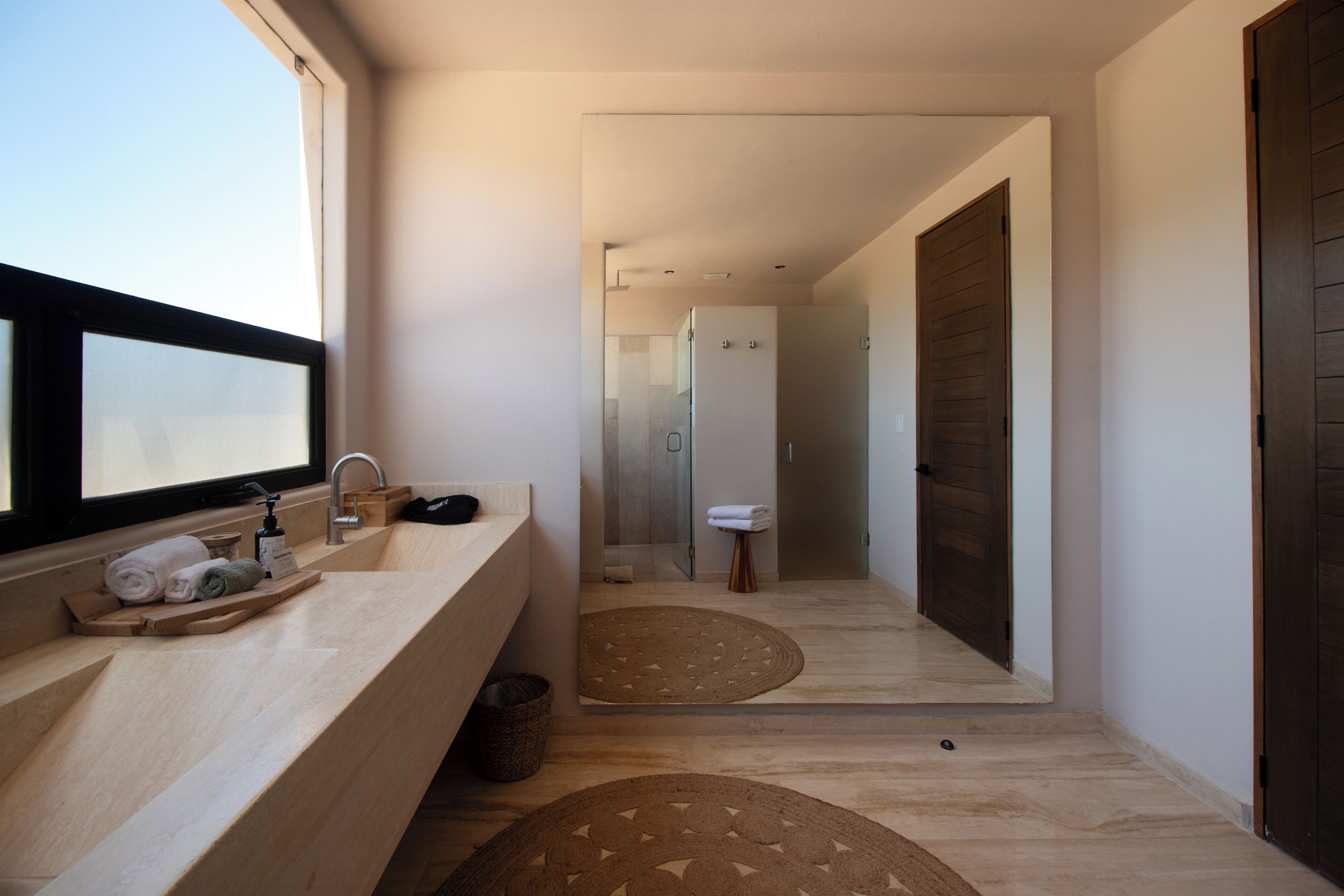 Un baño moderno con tocador de madera, una ventana y zona de ducha.