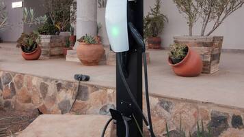 Estación de carga para vehículos eléctricos en un entorno exterior con escalones de piedra y plantas en macetas.