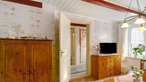 Een kamer met houten kasten, een televisie en een deur naar een andere ruimte.