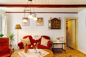 Un salon avec un canapé rouge, une table basse en bois, une lampe et un meuble.