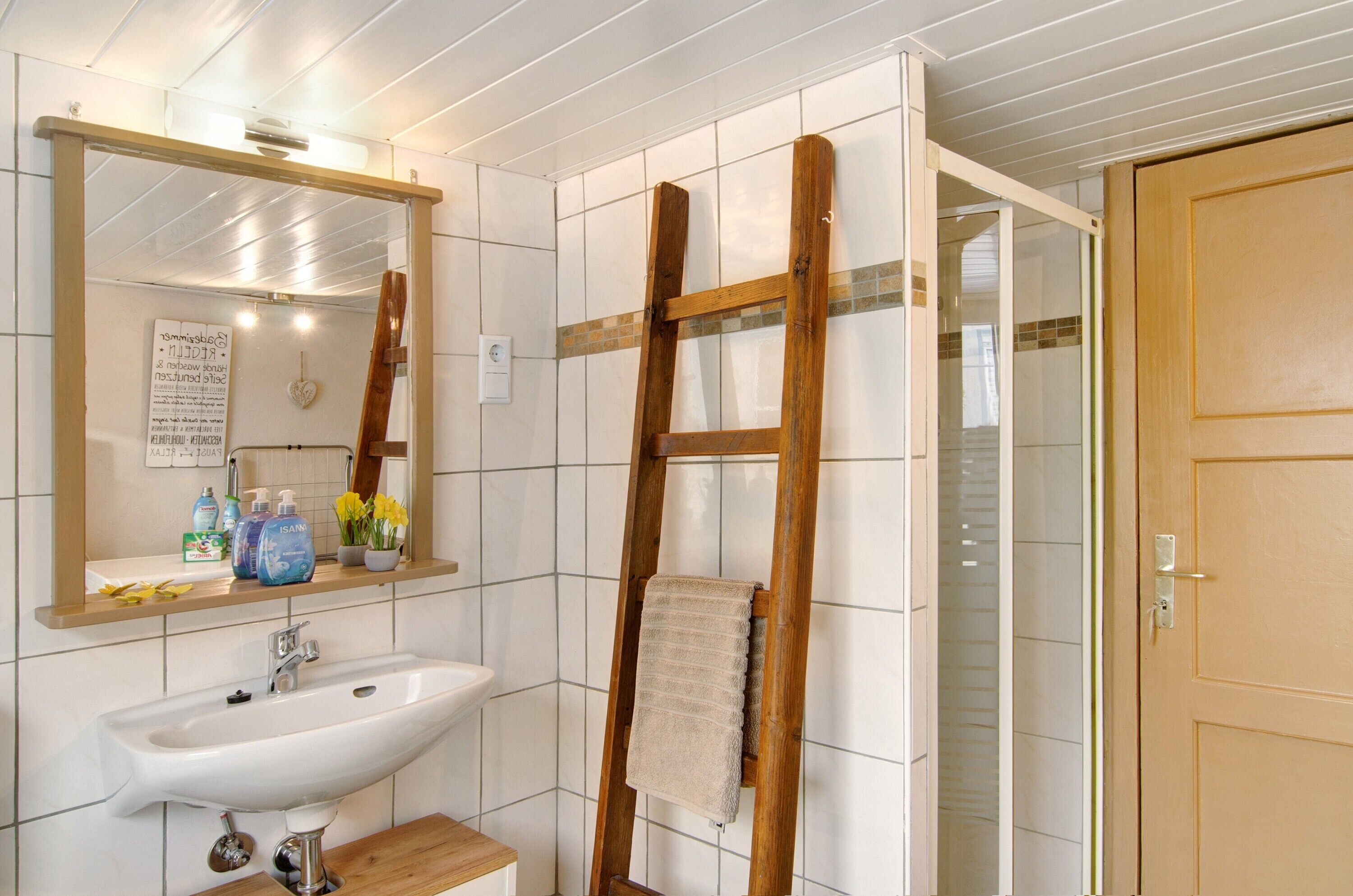 Ein Badezimmer mit Waschbecken, Spiegel und einer Holzleiter.