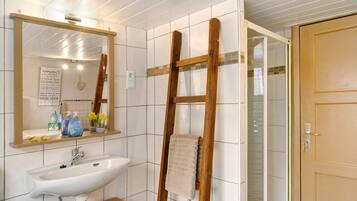 Ein Badezimmer mit Waschbecken, Spiegel und einer Holzleiter.