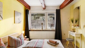 Een slaapkamer met een bed, nachtkastje en een raam met gordijnen.