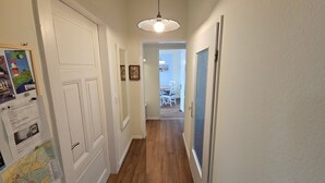 A hallway with white doors, a hanging light fixture, and a dining area in the background. - Apartment 'Hiddes Hus - Fuhrmann' with Wi-Fi (Borkum)
