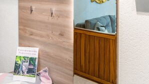 A room with a wooden wardrobe, a mirror, a framed picture, and a book on a table. - Holiday Apartment 'NaturPur' – Spacious, Quiet, Family-Friendly Retreat (Rheinau)