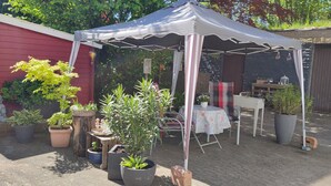 A red building with a white door, a white tent, and various potted plants. - Holiday Apartment 'NaturPur' – Spacious, Quiet, Family-Friendly Retreat (Rheinau)