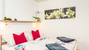 A neatly made bed with floral bedding, a red pillow, and a grey blanket. - Holiday Apartment 'NaturPur' – Spacious, Quiet, Family-Friendly Retreat (Rheinau)