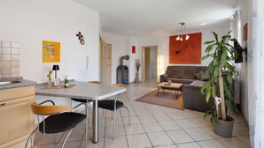 Una sala de estar moderna con un sofá, un comedor con una mesa y sillas, y una cocina con un fregadero y armarios.
