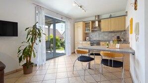 Cocina moderna con comedor, una planta en maceta y puerta corrediza de vidrio a un balcón.