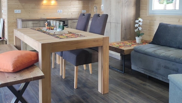 Un intérieur chaleureux avec une table à manger en bois, des chaises, un canapé et une fenêtre offrant une vue agréable.