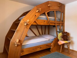 A wooden bunk bed with a built-in ladder, a plush toy, and a small shelf.