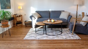Una sala de estar con un sofá gris, una mesa de centro redonda y una lámpara.