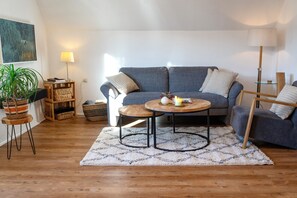 Un salon avec un canapé gris, une table basse ronde et une lampe.