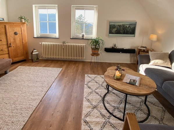 Un salon avec un canapé, une table basse, un radiateur et une fenêtre donnant sur un beau paysage.