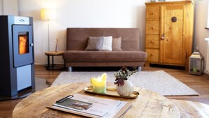 Una sala de estar con un sofá, un armario, una mesa con una vela y una chimenea.