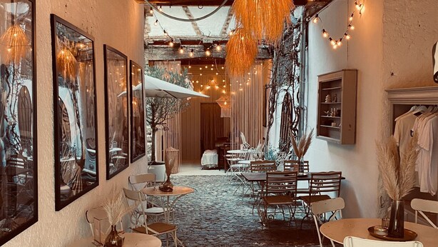 A cozy café with tables and chairs, framed artwork on the walls, and string lights. - "Holiday Apartment Frida" in the heart of Burkheim (Vogtsburg)