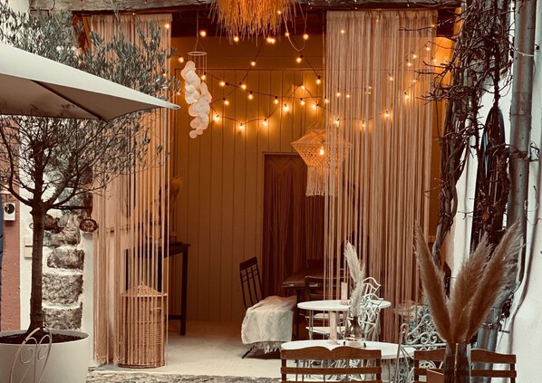 An outdoor seating area with a table and chairs, a hanging light fixture, and a tree. - "Holiday apartment Kahlo" (Vogtsburg)