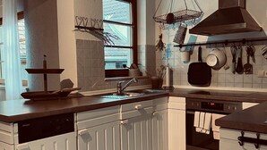 Uma cozinha com armários brancos, lava-louças, pia e diversos utensílios de cozinha pendurados na parede.