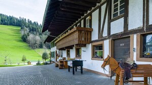 Een traditionele chalets met een houten balkon, een paardenstal en een geplaveid erf.