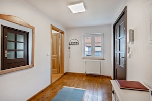 Un pasillo con suelo de madera, un radiador, una ventana y una puerta.